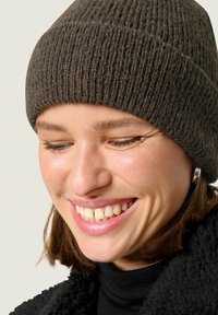 Braune, gerippte Strickmütze mit eng anliegendem Schnitt, getragen von einer Person mit kurzem Haar, vor einem neutralen Hintergrund.