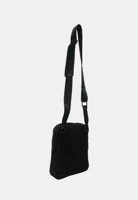 Borsa nera a tracolla di forma rettangolare, realizzata in tessuto morbido, con chiusura a zip, tracolla regolabile e design minimalista.