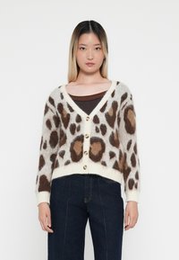 Luipaardprint cardigan met een zachte, fluffy textuur, V-hals, knoopsluiting en ribgebreide zoom. Kleuren zijn onder andere crème, bruin en beige accenten.