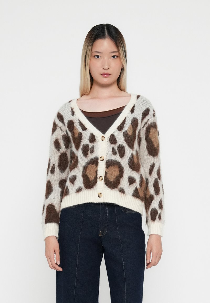 Luipaardprint cardigan met een zachte, fluffy textuur, V-hals, knoopsluiting en ribgebreide zoom. Kleuren zijn onder andere crème, bruin en beige accenten.
