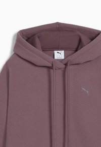 Fioletowy nadrukowany kaptur, z prążkowaną teksturą, sznurkami i małym srebrnym logo Puma. Ma metkę wewnątrz kołnierza.