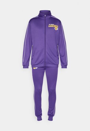 Violets treniņtērps no gluda poliestera, ar baltu svītru gar piedurknēm un biksēm, ar Los Angeles Lakers logotipu uz krūtīm un kājām.