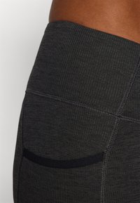 Dark gray leggings with a ribbed texture, featuring a wide waistband and contrasting black accent on the side for added detail.