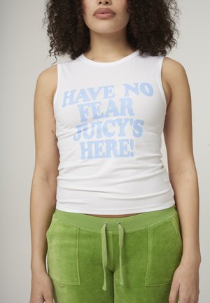 Débardeur sans manches blanc avec le texte bleu "N'AYEZ PAS PEUR, JUICY EST LÀ !" et un pantalon de sport vert avec cordon de serrage, tissu texturé et poches latérales.
