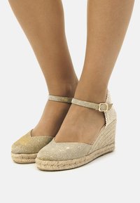 Espadrillas con zeppa intrecciata in oro e argento, dotate di cinturino alla caviglia; tomaia in tessuto texturizzato e zeppa rivestita in juta; design open-toe.