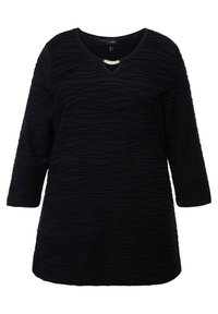 Marinblå tunika med V-hals och 3/4-långa ärmar, med texturerade vågiga mönster och en liten dekorativ detalj vid halsringningen.