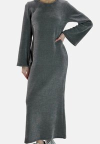 Lungo abito grigio in tessuto strutturato. Presenta una scollatura rotonda, maniche lunghe a campana, tasche laterali e arriva alle caviglie.
