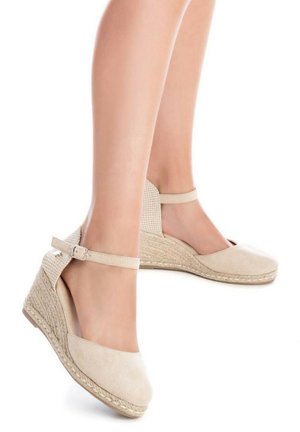 Alpargatas de cuña beige con parte superior de ante y suela de yute trenzado. Presenta una correa alrededor del tobillo y un diseño de malla recortada en los laterales.