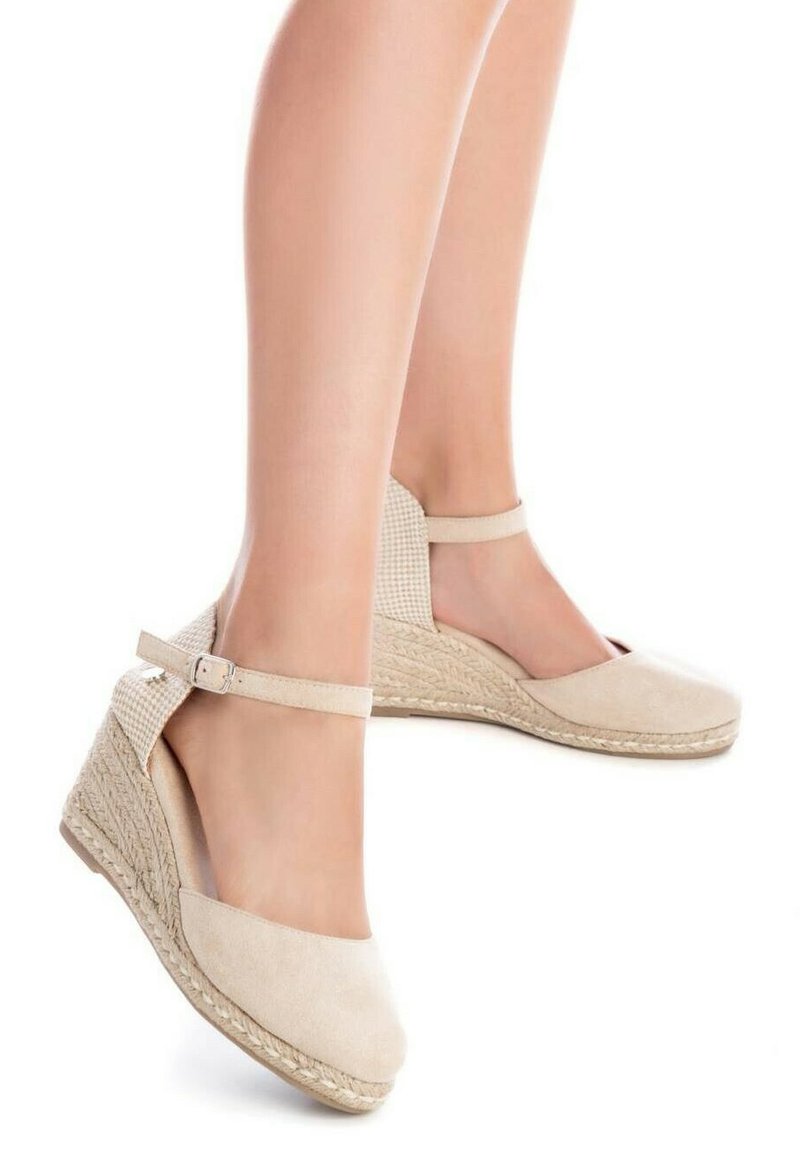 Alpargatas de cuña beige con parte superior de ante y suela de yute trenzado. Presenta una correa alrededor del tobillo y un diseño de malla recortada en los laterales.