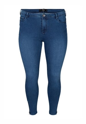 Donkere blauwe strakke spijkerbroek met voorste knoop en rits, vijf zakken en kleine ritsen aan de enkels.