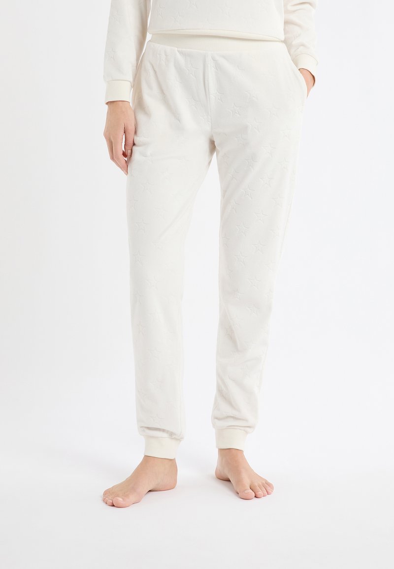 Jasnokremowe spodnie dresowe z miękkiego materiału z wzorem w gwiazdki. Posiadają elastyczną talię i ściągacze dla dopasowania.