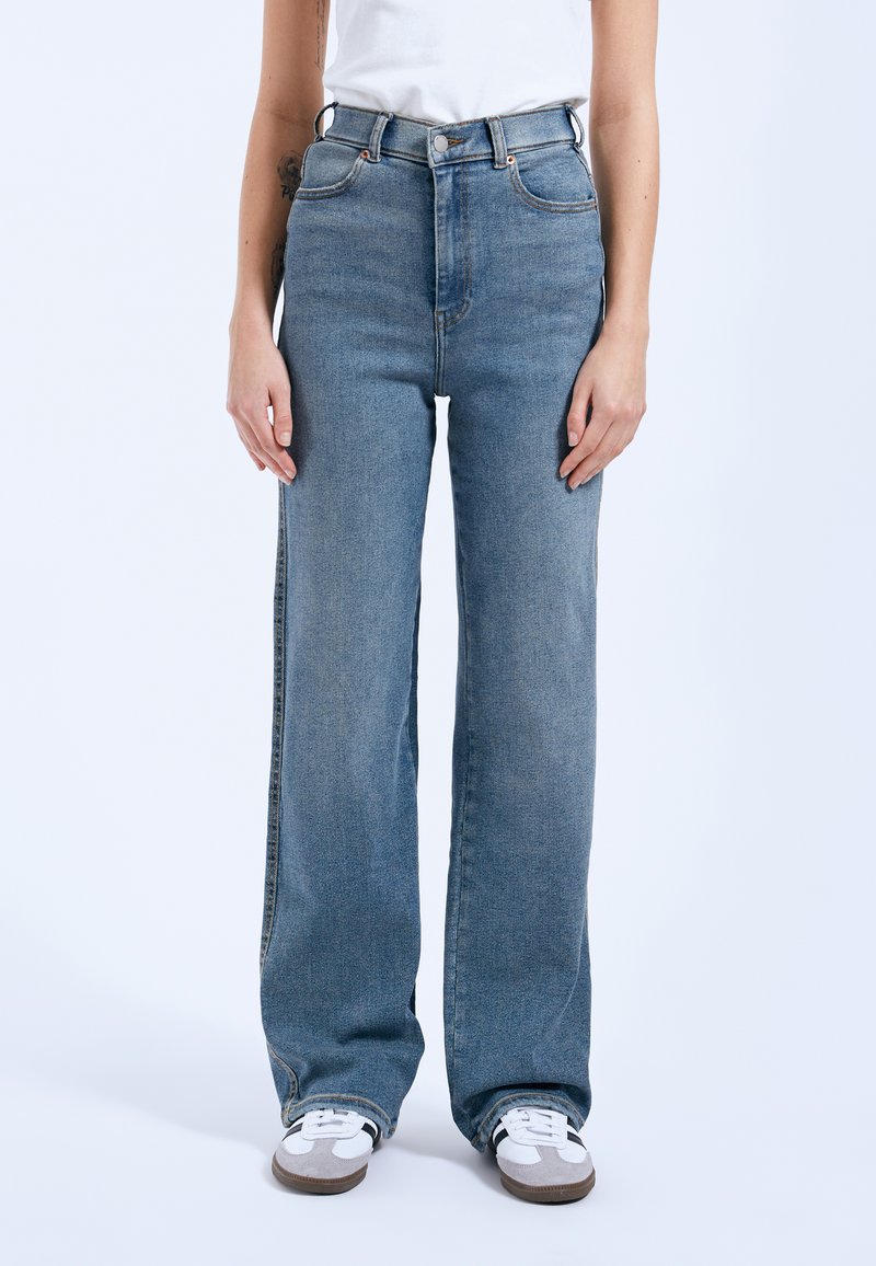 Jeans de tiro alto en azul con un diseño de pierna ancha, hechos de tela de denim. Incluyen presillas para cinturón y un cierre de cremallera frontal.