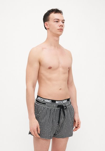 Boxeri cu carouri alb-negru, cu un brâu elastic, cu logo-ul "Moschino", detaliu cu fundiță și buzunare laterale.