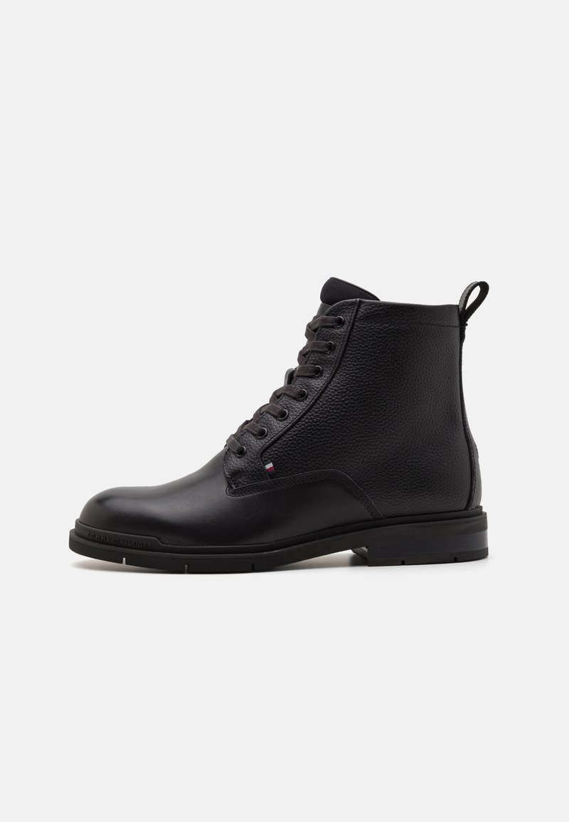 Bottine en cuir noir avec tige texturée, bout rond et laçage à l'avant. Présente une languette et un discret logo sur le côté.