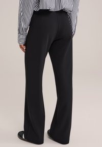 Črne hlače ravnega kroja iz gladkega materiala, z zmerno visokim pasom in čistim dizajnom, v kompletu z dolgem rokavom krojenim srajcem s črtami.