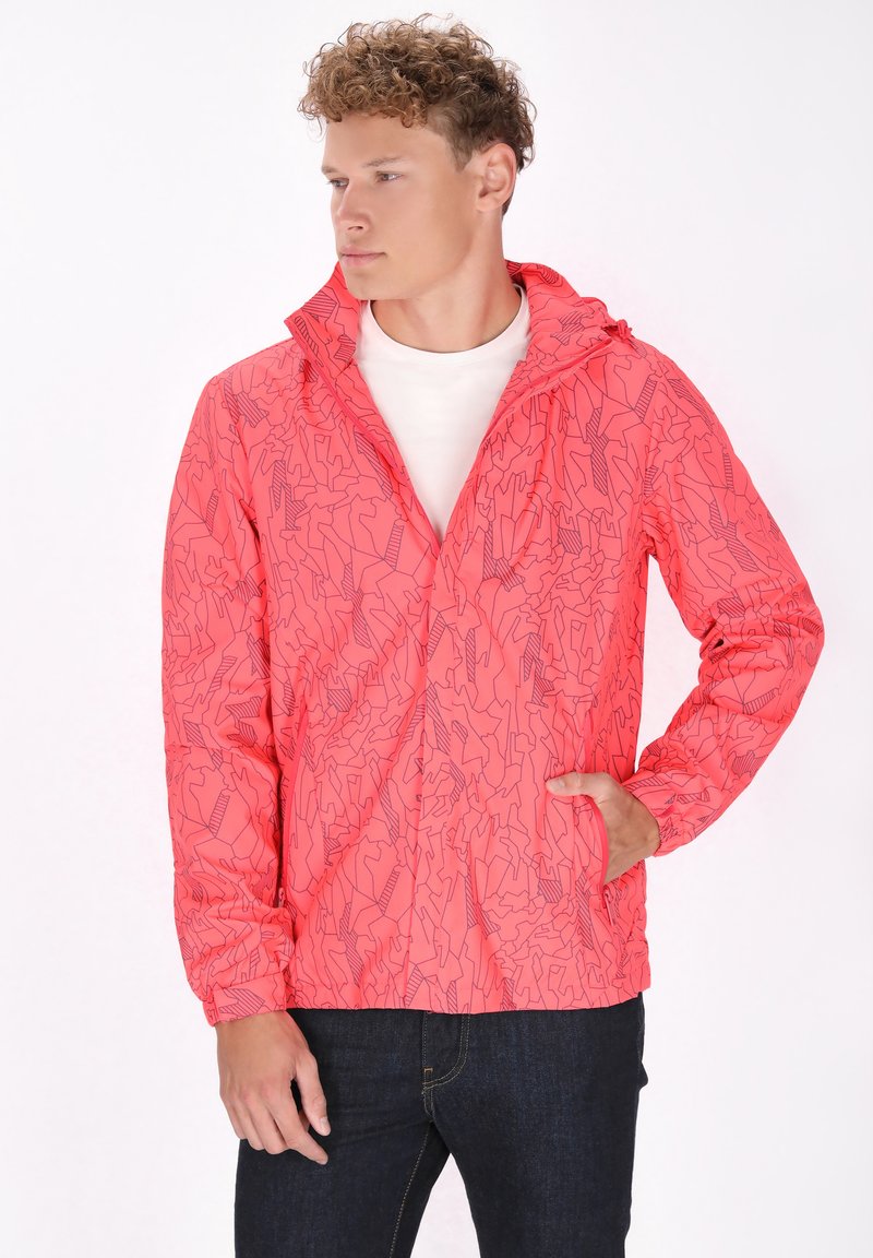 Jasne ružová bunda s abstraktným vzorom čiar, kapucňou, zipsom a elastickými manžetami. Upravena nad bielou košeľou a v kombinácii s tmavými džínsami.
