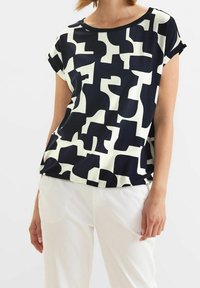 Kortärmad topp i marinblått och krämfärgat med ett abstrakt mönster, rund halsringning och lös passform. Tillverkad av mjukt, lätt tyg.