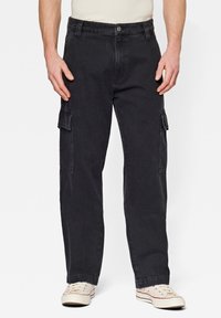 Pantaloni cargo neri in cotone con una vestibilità rilassata, dotati di due tasche laterali e chiusura a bottone. Il tessuto ha una consistenza liscia.