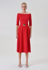 Rotes schulterfreies Kleid mit Dreiviertelärmeln, tailliertem Oberteil und einem goldenen Gürtelschnalle-Detail. Glatter Stoff, knielanger Rock.