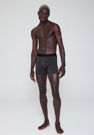 Sorte stribede boxershorts lavet af blødt stof, med et tætsiddende design, elastisk talje og uden synlige mønstre eller logoer.