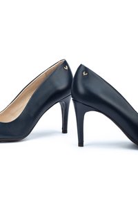 Pumps alti in pelle blu navy con una texture liscia, punta appuntita e un logo in oro sul tallone. Design classico con un'altezza moderata.
