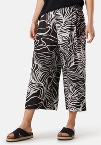 Zwart-witte culottes hebben een vloeiende stof met een golvend zebra-patroon, zijzakken en een elastische tailleband voor comfort.