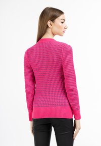 Maglione magenta lavorato a maglia con motivo strutturato e polsini a coste. Caratterizzato da un collo arrotondato e una silhouette aderente.