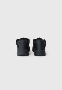 Black sneakers with a synthetic leather upper, padded collar, and textured rubber sole, featuring a smooth finish and minimal design.