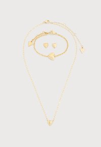 Σετ κοσμημάτων σε χρυσό τόνο που περιλαμβάνει κολιέ και βραχιόλι με κρεμαστά καρδιές, καθώς και ταιριαστά σκουλαρίκια σε σχήμα καρδιάς. Περιλαμβάνονται περίτεχνες λεπτομέρειες.