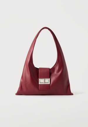 Sac à main en cuir bordeaux doux avec une large bandoulière unique et un fermoir rectangulaire en métal argenté à l'avant.