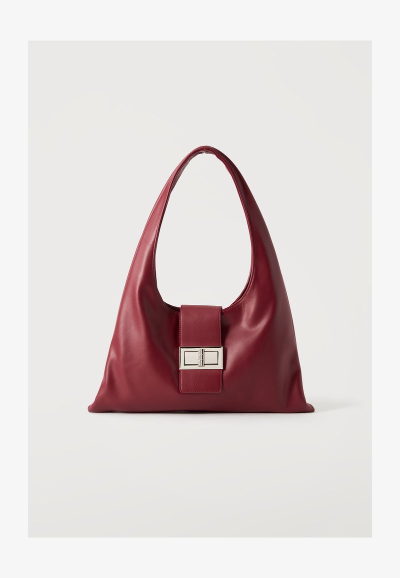 Sac à main en cuir bordeaux doux avec une large bandoulière unique et un fermoir rectangulaire en métal argenté à l'avant.