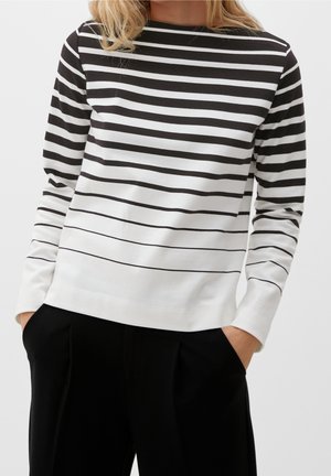 Maglia a maniche lunghe a righe in bianco e nero, con righe orizzontali, scollatura rotonda e tessuto morbido. Abbinata a pantaloni neri.