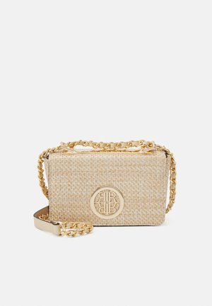 Pieni beige kudottu olkalaukku, jossa on kullanvärinen ketjuhihna ja pyöreä kultainen logopainatus edessä.