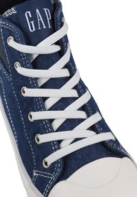 Zapatilla alta de denim azul con cordones blancos, material de lona, que presenta una puntera de goma y ojales plateados. Logotipo en la lengüeta.