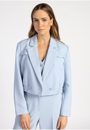 Veste cropped bleu clair avec un col structuré, deux poches avant et deux boutons de fermeture, fabriquée dans un tissu lisse et texturé.