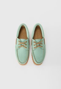 Pair of mint green leather boat shoes with tan laces and cushioned collars, viewed from above on a plain white background.
