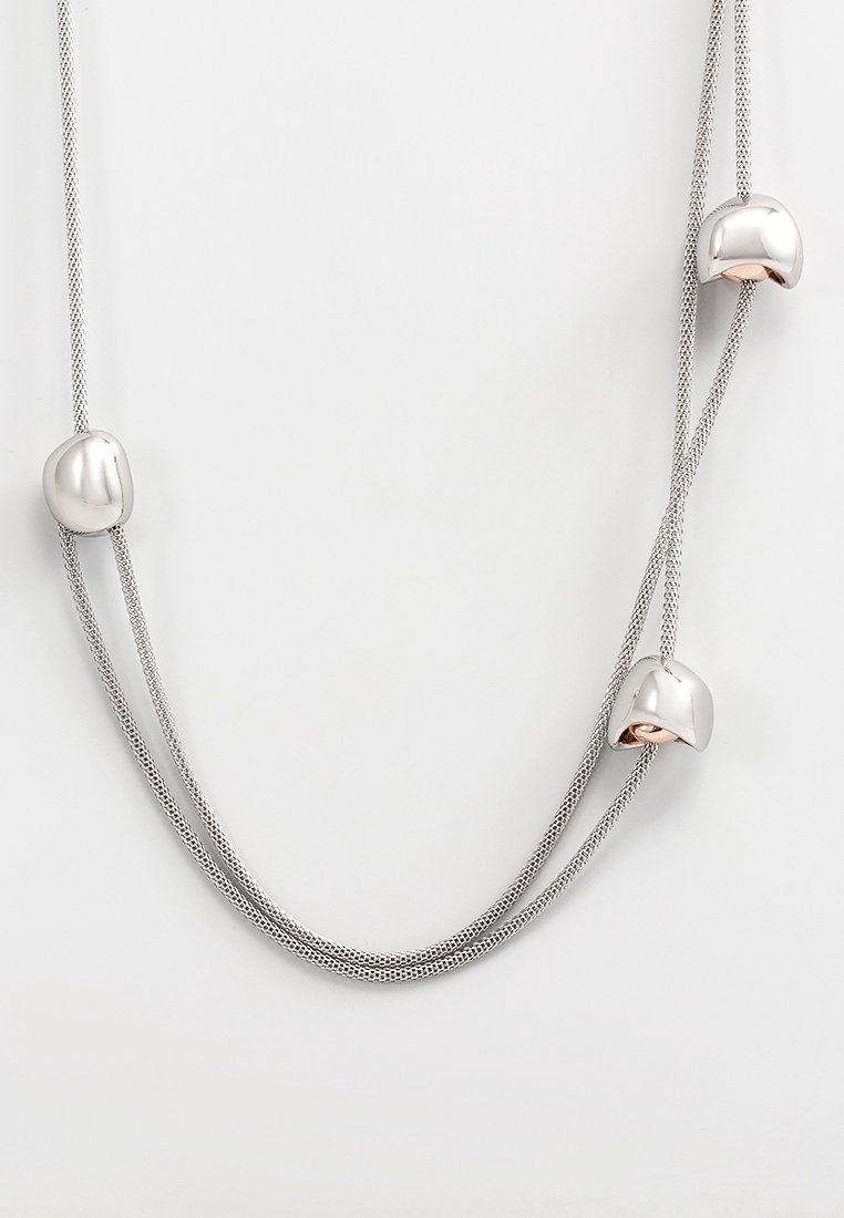 Collier à double chaîne en argent avec trois perles en argent de forme irrégulière espacées le long des chaînes sur un fond blanc.