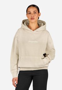 Beżowa bluza z kapturem z miękkiego materiału, z przednią kieszenią, kapturem ze sznurkiem oraz wytłoczonym logo "pegador" na piersi.