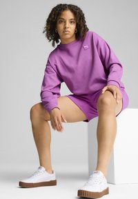Set di felpa e pantaloni corti in cotone viola, con scollo rotondo, vestibilità comoda e sneakers bianche con suole in gomma marrone.