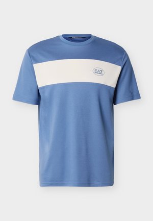 Sininen lyhythihainen t-paita, jossa on leveä valkoinen vaakaraita rinnassa ja vasemmalla puolella pieni EA7 Emporio Armani -logo.