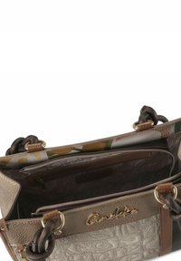 Strukturierte beige-braune Handtasche mit floral gemustertem Innenfutter, zwei Griffen und einer Innentasche mit Metallreißverschluss. Goldfarbenes Logodetail auf der Vorderseite.