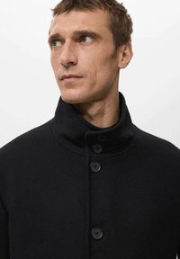 Czarny wełniany płaszcz z wysokim kołnierzem, pięcioma guzikami i gładką fakturą. Projekt jest prosty i nowoczesny.