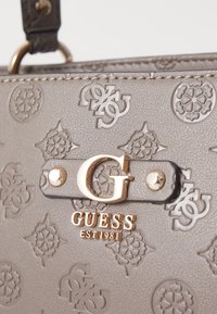 Grå faux læder håndtaske med præget mønster, en guldtonet logo-lås og et struktureret design med metalaccenter.