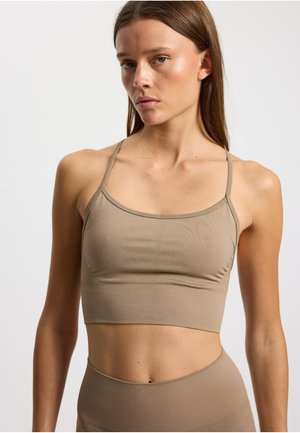Jasnobrązowy crop top z cienkimi ramiączkami, wykonany z materiału o prążkowanej teksturze, charakteryzujący się dopasowanym krojem i minimalnymi detalami przeszycia.