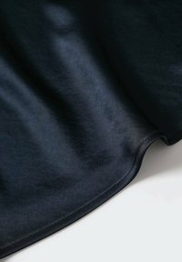 Zwarte stof met een gladde textuur, die soepel valt. De rand is zacht gebogen met een nette, gestikte zoom.