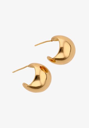 Par af skinnende, halvmåneformede guldringe med stifter til piercede ører mod en hvid baggrund.