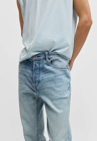 Jasnoniebieskie dżinsy z luźnym krojem, z przednimi kieszeniami, odcieniem w stylu vintage oraz kontrastowym przeszyciem wokół pasa.