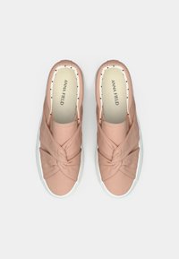 Sneakers slip-on in tela rosa pallido con design frontale attorcigliato e suola in gomma bianca. L'interno è foderato con pois neri.