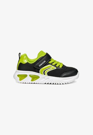 Scarpe da ginnastica nere e verde neon con tessuto a rete, una fascia in Velcro e suola in gomma bianca con dettagli distinti di trazione verdi.