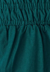 Tissu bleu-vert avec une texture froncée, affichant une finition lisse et un éclat subtil. Le matériau semble léger et respirant.